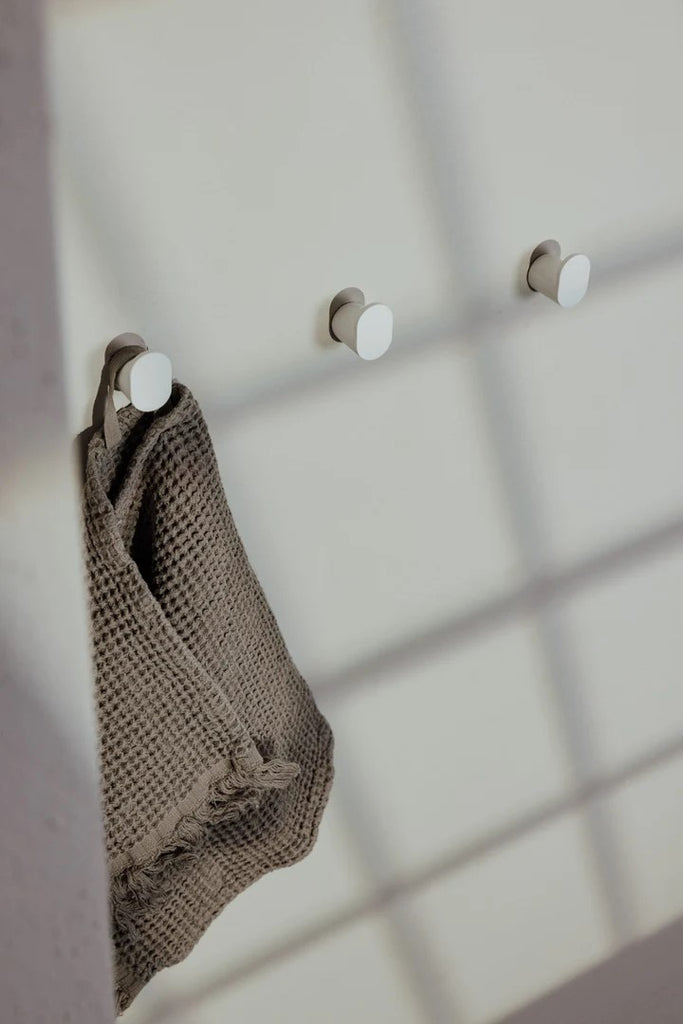 Wandhaken rund weiß aus Metall als Handtuchhalter.