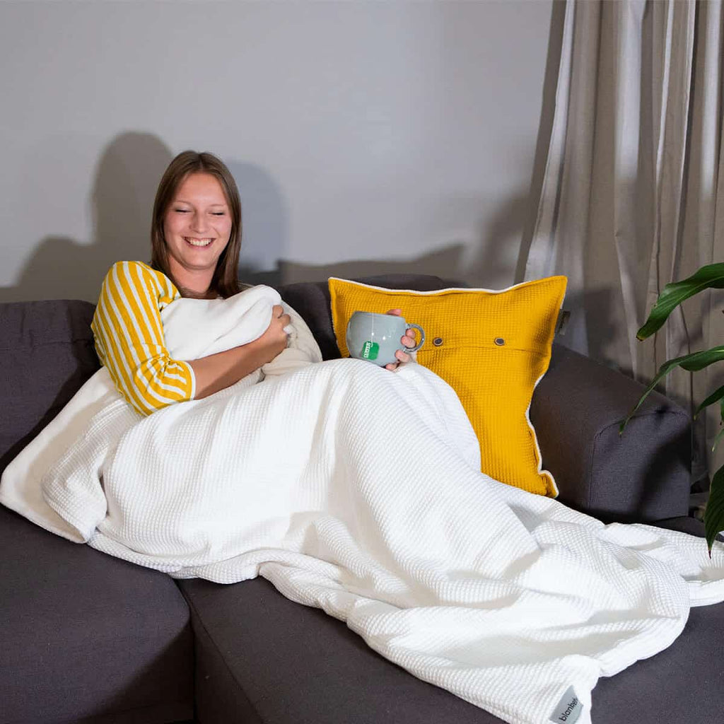 Kuschelige weiche warme Decke individualisierbar mit Bestickiung  in weiß auf dem Sofa.